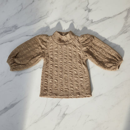 Girl's top featuring a floral jacquard pattern and lantern sleeves.